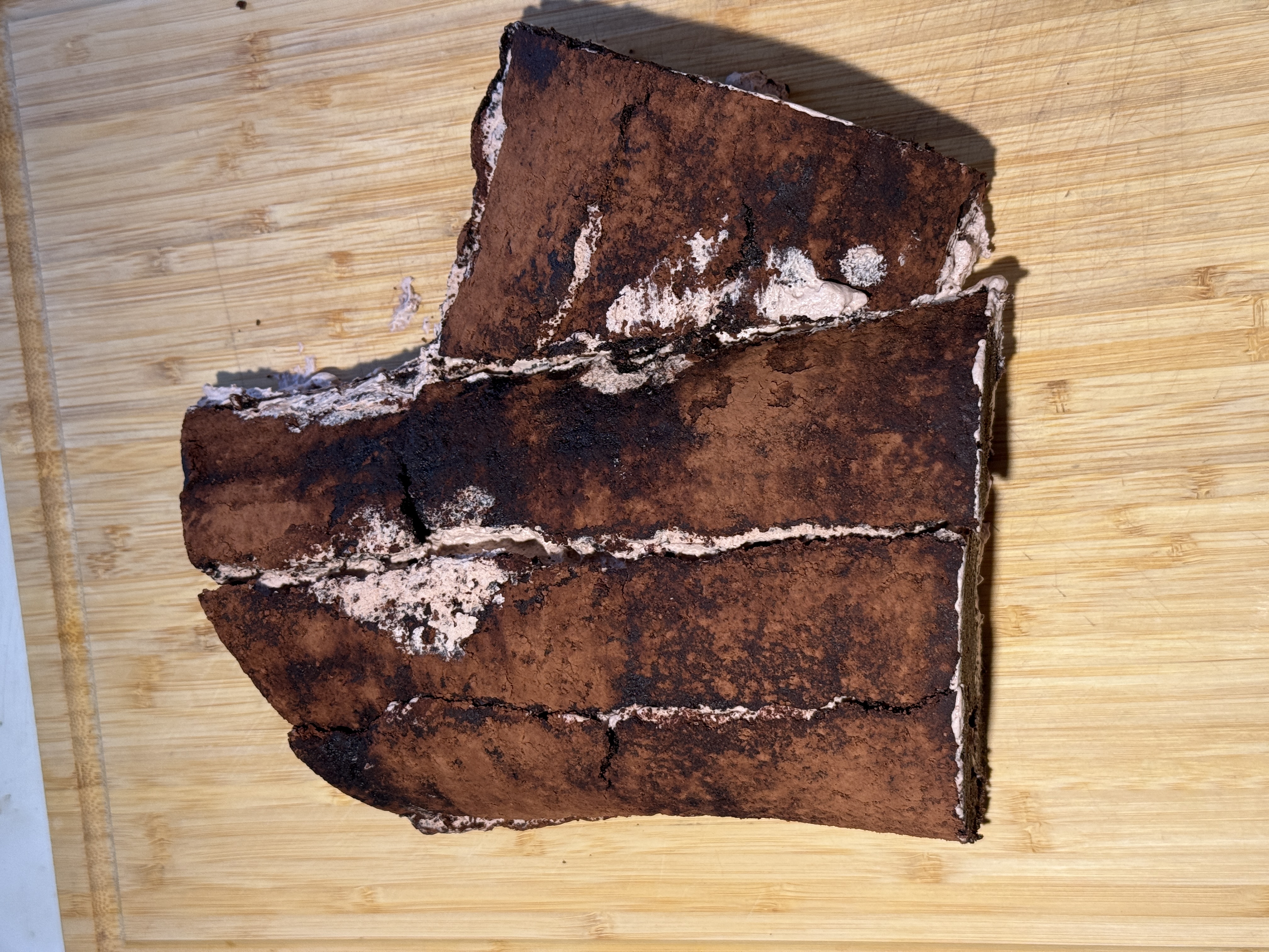 Unrolled chocolate cake split into several vertical sections, with whipped cream filling visible in the cracks.